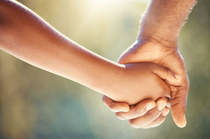 Photo of a child holding hands with an adult