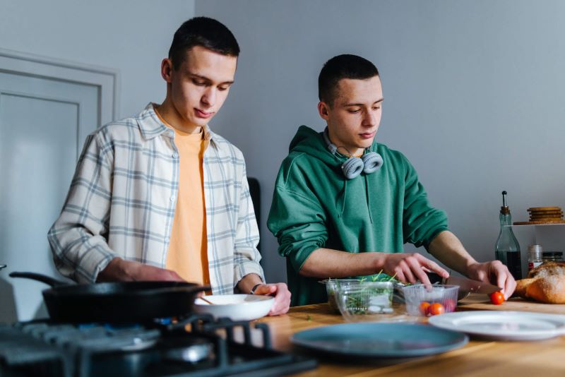 A photo of twin teenage boys making their lunch in the kitchen