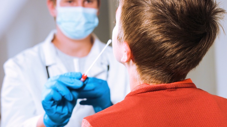 A doctor testing a child with a cotton swab.