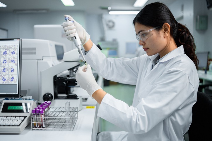 A scientist studying something on a microscope.