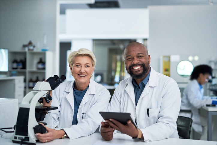 Scientists with microscopes smiling.