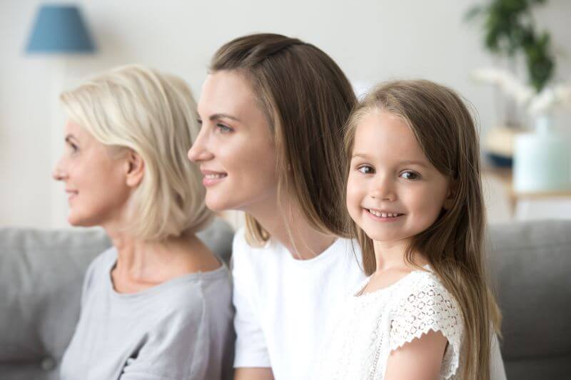 A photo of two women and a girl sitting on a couch.